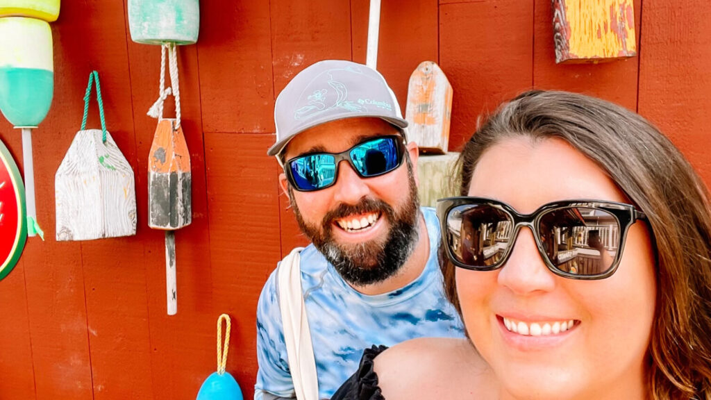 Ruth and Orlando standing in front of a wall of buoys